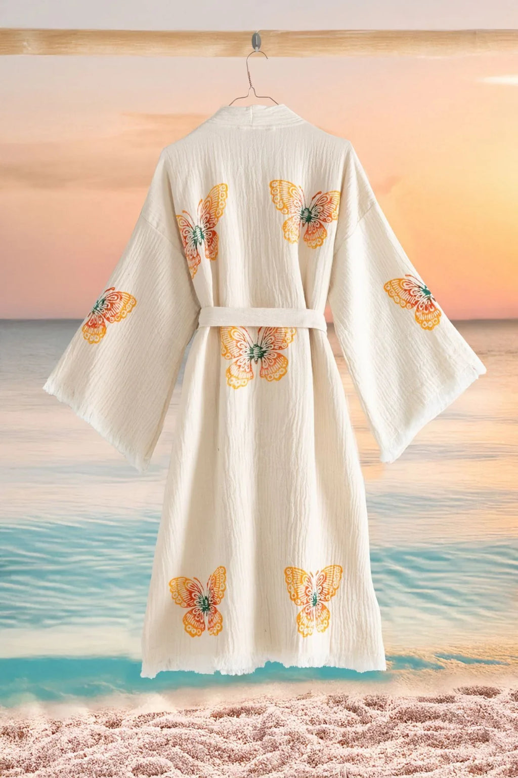 Weißer Kimono mit bunten Schmetterlingsmustern vor Strandkulisse