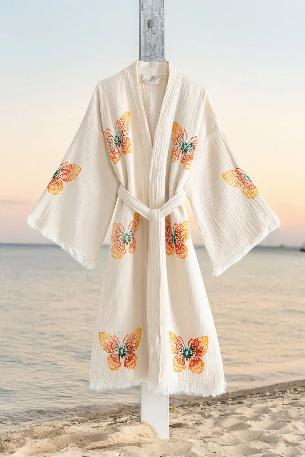 Weißer Kimono mit bunten Schmetterlingsmustern am Strand
