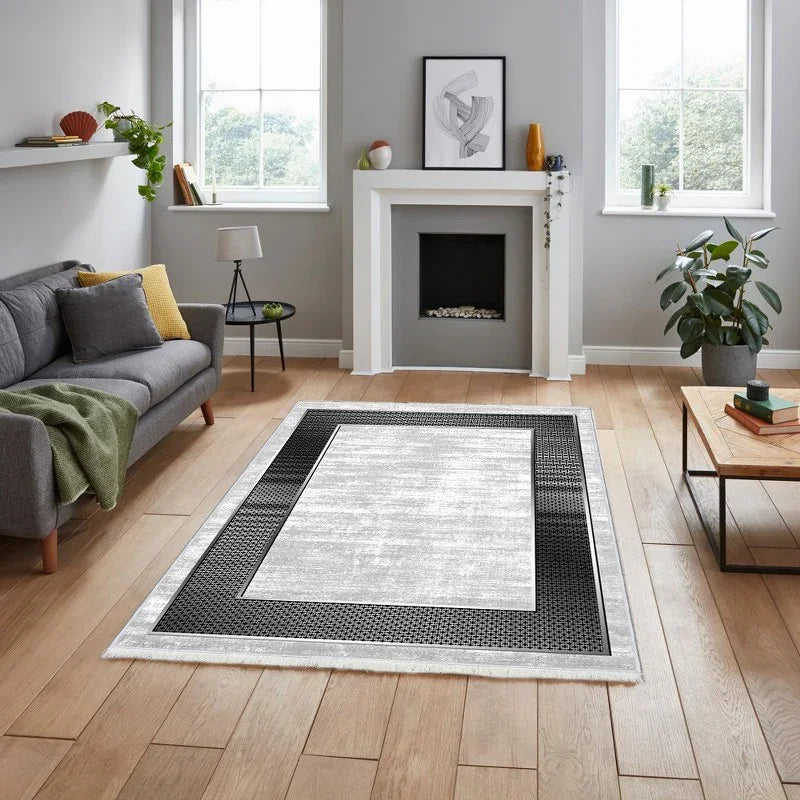 Modern washable area rug with black and gray geometric border in a bright living room