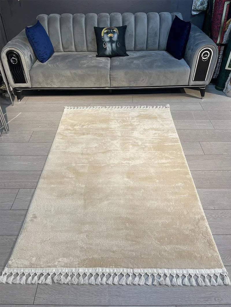 Beige waschbarer Teppich mit Fransen vor grauem Sofa, modernes Wohnzimmerdesign